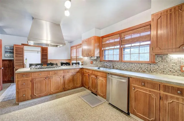 a kitchen with stainless steel appliances granite countertop a sink a stove and a wooden floors