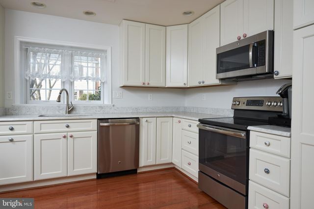 a kitchen with granite countertop white cabinets stainless steel appliances and a sink