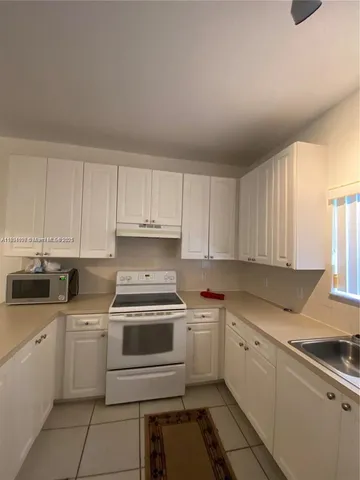 a kitchen with cabinets appliances a sink and a window