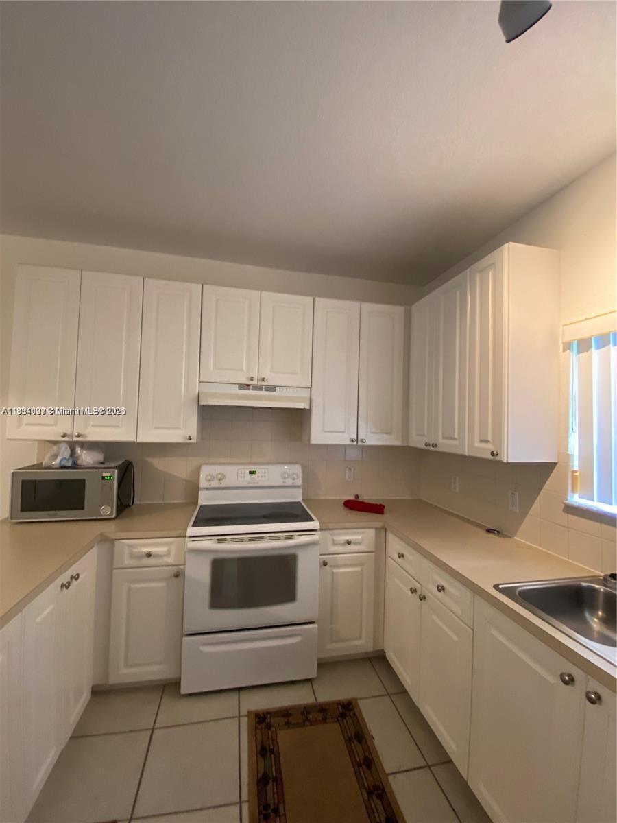 4802 Washington Street, Unit 14 Hollywood, FL 33021 - Photo 8 of 14 a kitchen with cabinets appliances a sink and a window