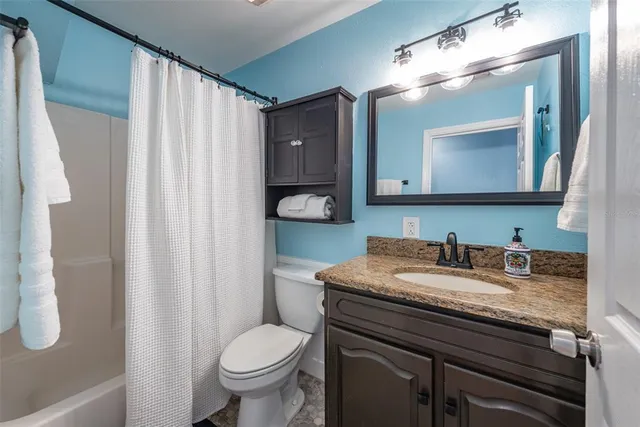 a bathroom with a granite countertop sink toilet and mirror