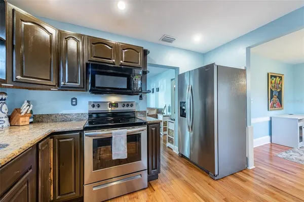 a kitchen with granite countertop wooden cabinets stainless steel appliances and a wooden floor