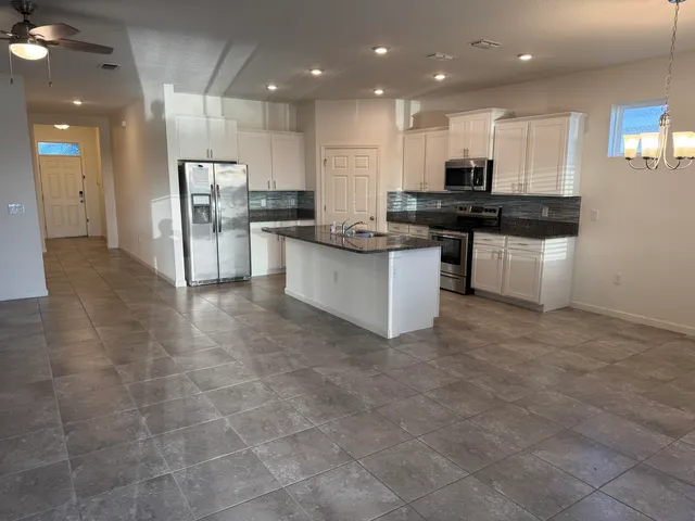 a kitchen with kitchen island granite countertop a sink cabinets and stainless steel appliances