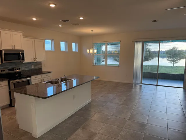 a kitchen with kitchen island granite countertop a sink and a stove top oven