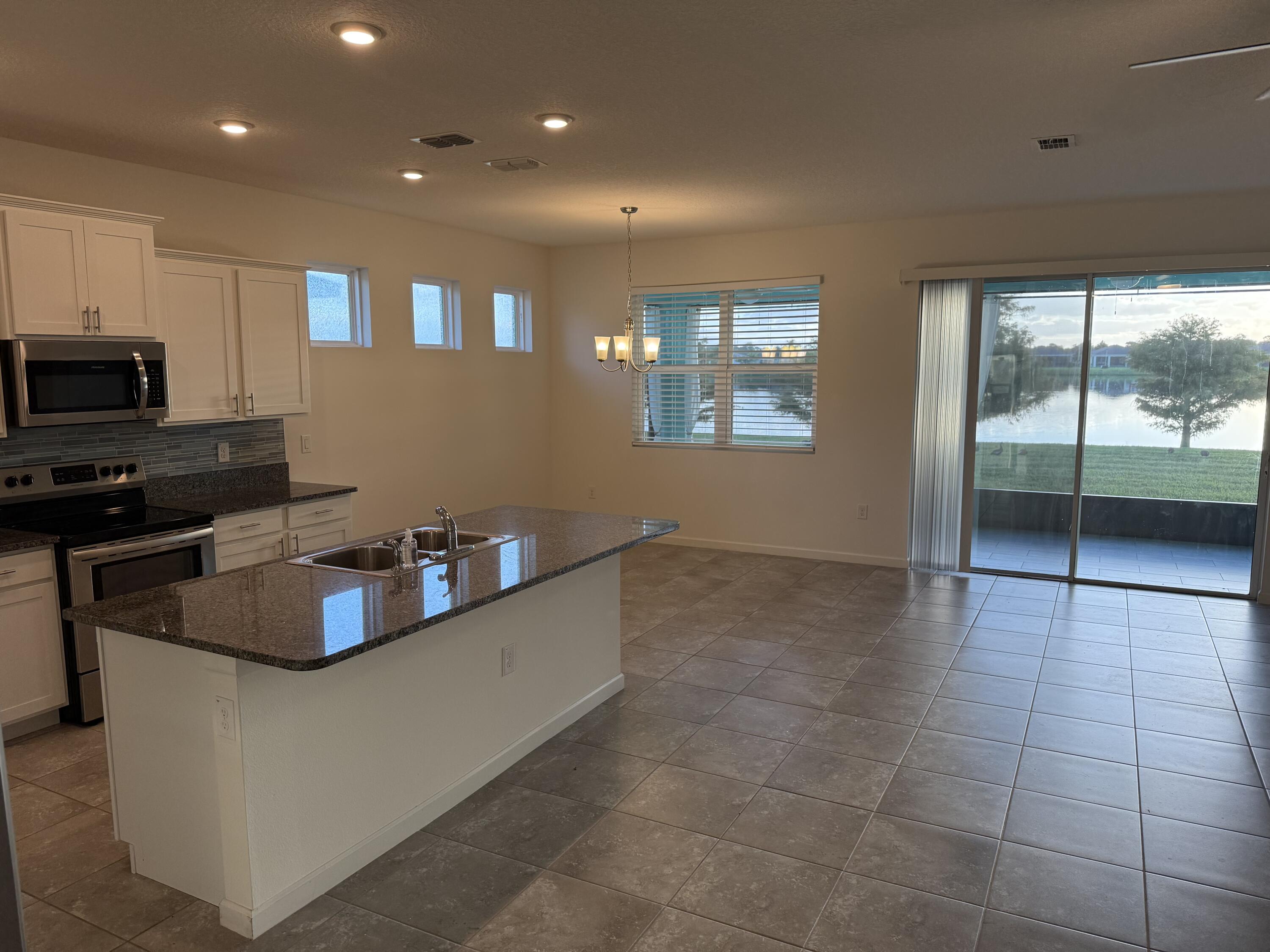 2608 Crowned Eagle Circle Southwest Vero Beach, FL 32962 - Photo 4 of 13 a kitchen with kitchen island granite countertop a sink and a stove top oven