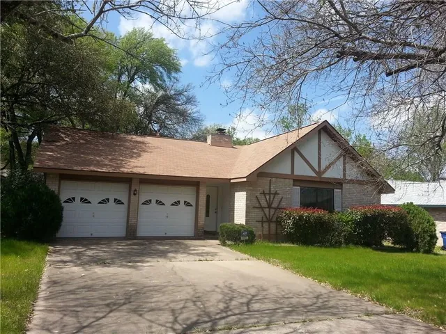 a view of a house with a yard and large tree