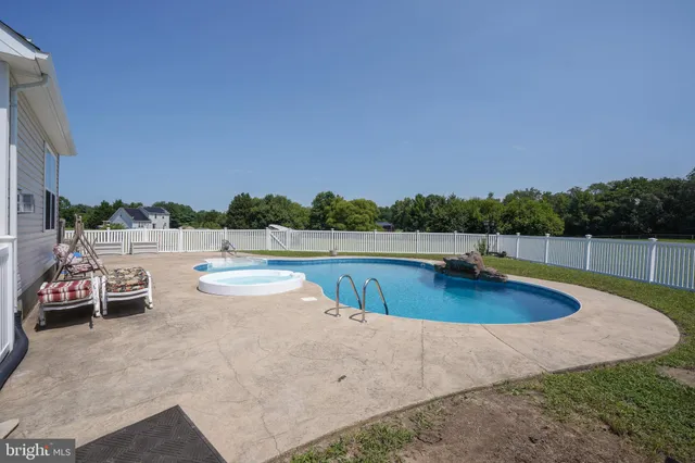 a view of a swimming pool with a patio and a yard
