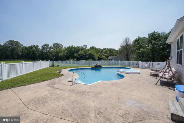 a view of a swimming pool with a bench and trees in the background