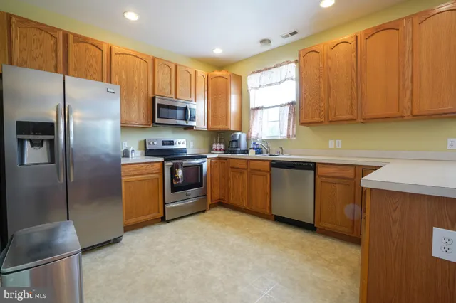 a kitchen with stainless steel appliances granite countertop a stove a sink dishwasher a refrigerator and a microwave