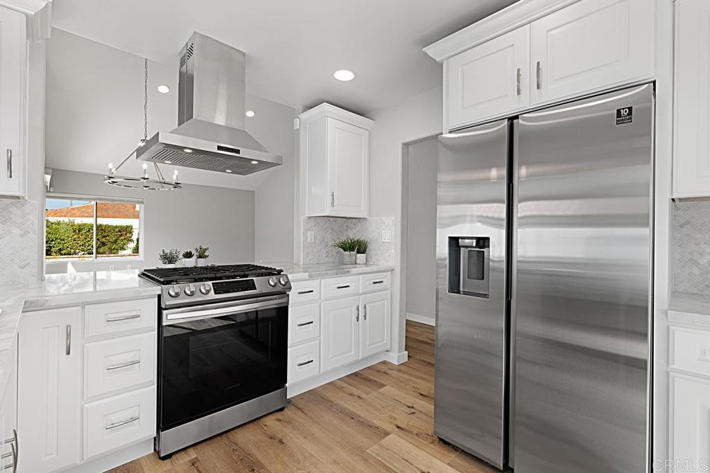 4710 Galicia Way Oceanside, CA 92056 - Photo 12 of 46 a kitchen with cabinets stainless steel appliances and wooden floor