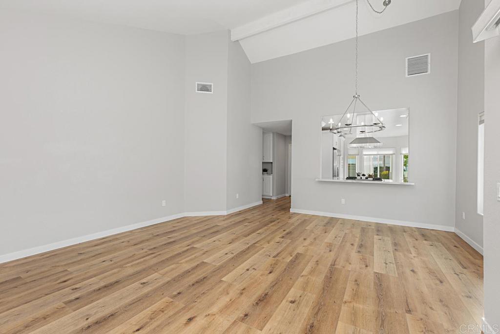 4710 Galicia Way Oceanside, CA 92056 - Photo 7 of 46 a view of kitchen and empty room with wooden floor