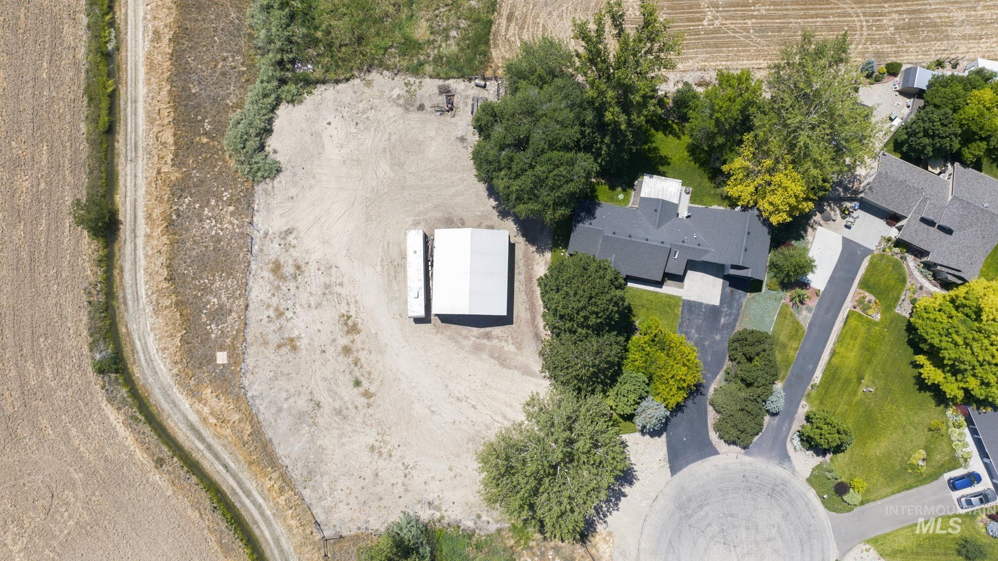 24864 Coventry Drive Caldwell, ID 83607 - Photo 35 of 49 Expansive property featuring a modern residential structure, a detached outbuilding, mature trees, and a paved driveway within a cul-de-sac