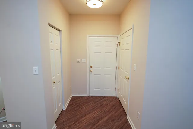 a view of a hallway with wooden floor and closet area