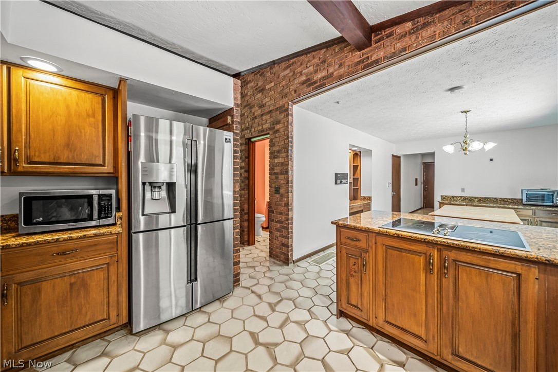 12200 Caves Road Chesterland, OH 44026 - Photo 15 of 43 Kitchen with brick wall, light tile floors, beam ceiling, appliances with stainless steel finishes, and a textured ceiling