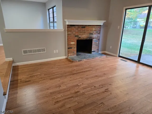 a view of empty room with wooden floor and fireplace