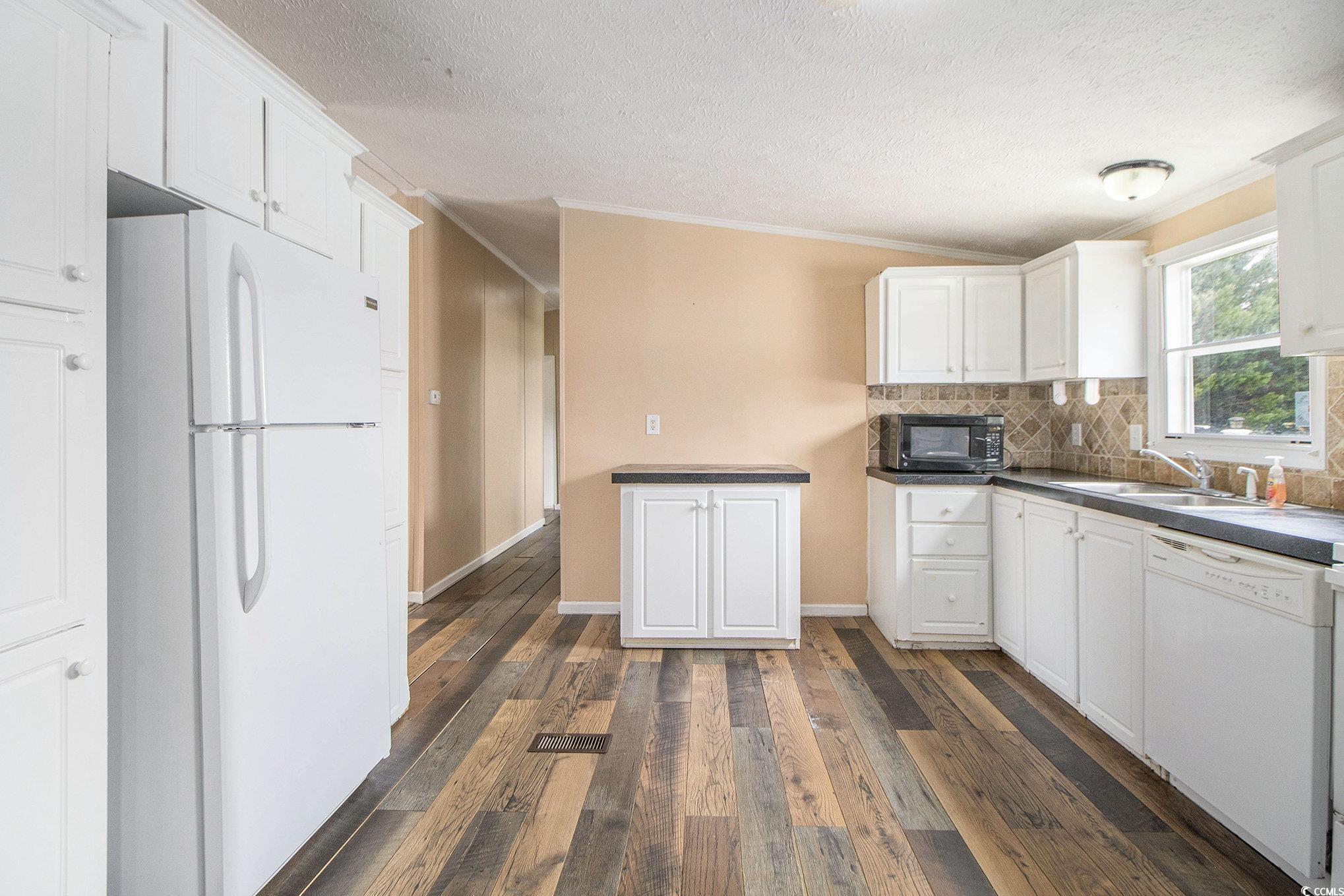 3804 Stern Drive Conway, SC 29526 - Photo 15 of 38 Kitchen featuring crown molding, white appliances, white cabinets, dark wood-type flooring, and decorative backsplash