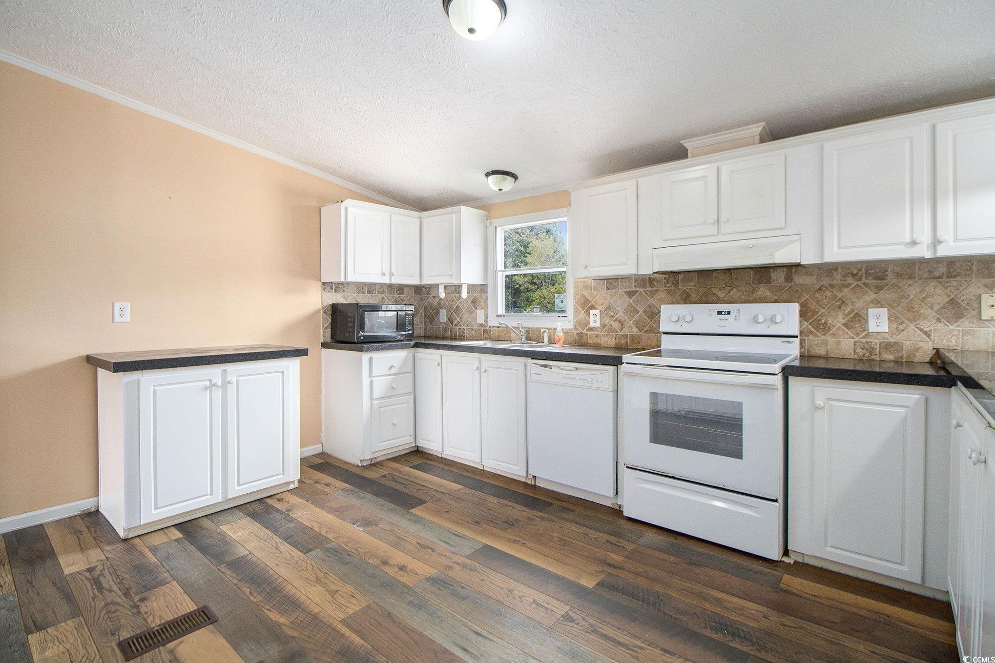 3804 Stern Drive Conway, SC 29526 - Photo 16 of 38 Kitchen with white appliances, white cabinets, decorative backsplash, dark countertops, and a textured ceiling