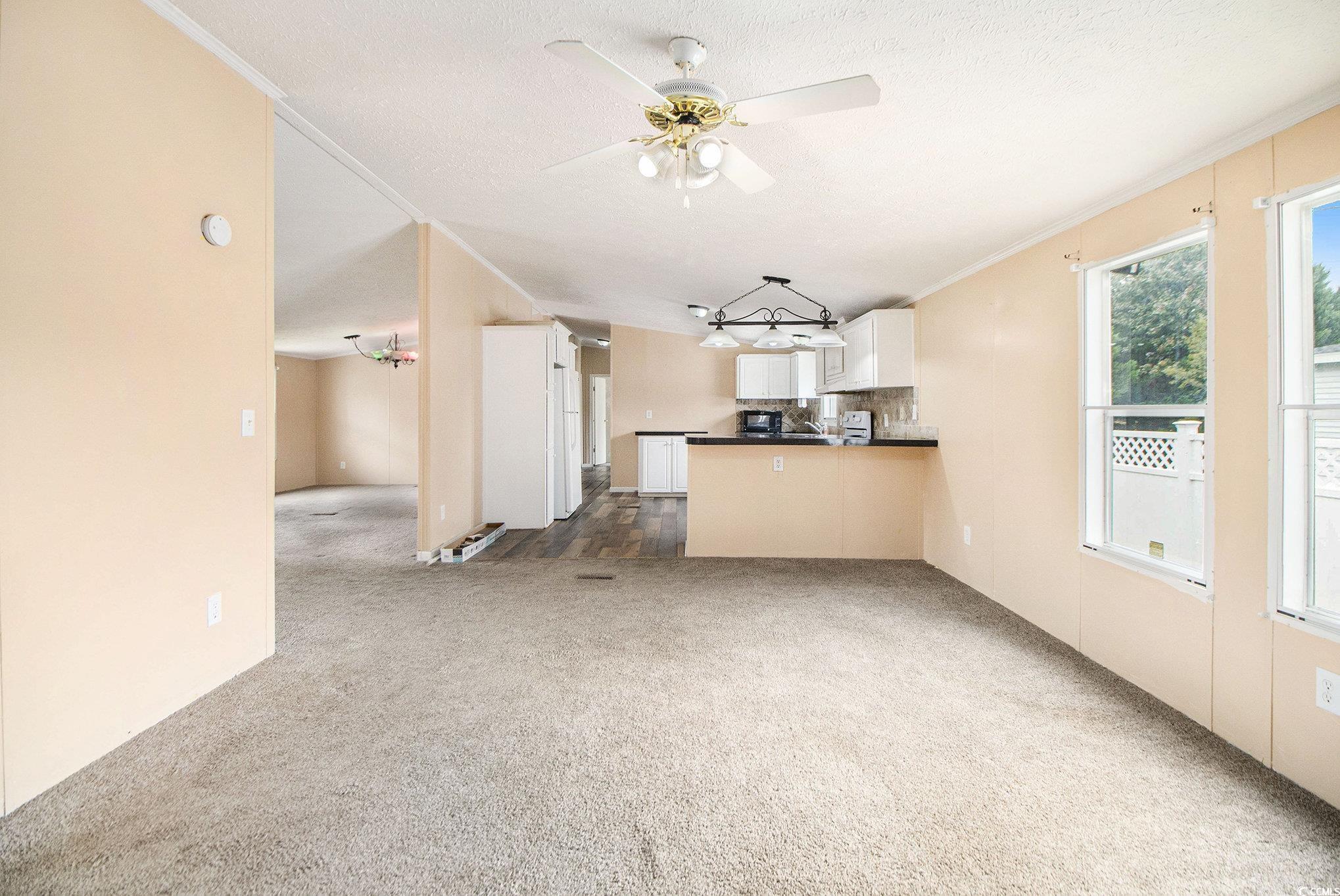 3804 Stern Drive Conway, SC 29526 - Photo 9 of 38 Unfurnished living room featuring dark carpet, crown molding, and ceiling fan
