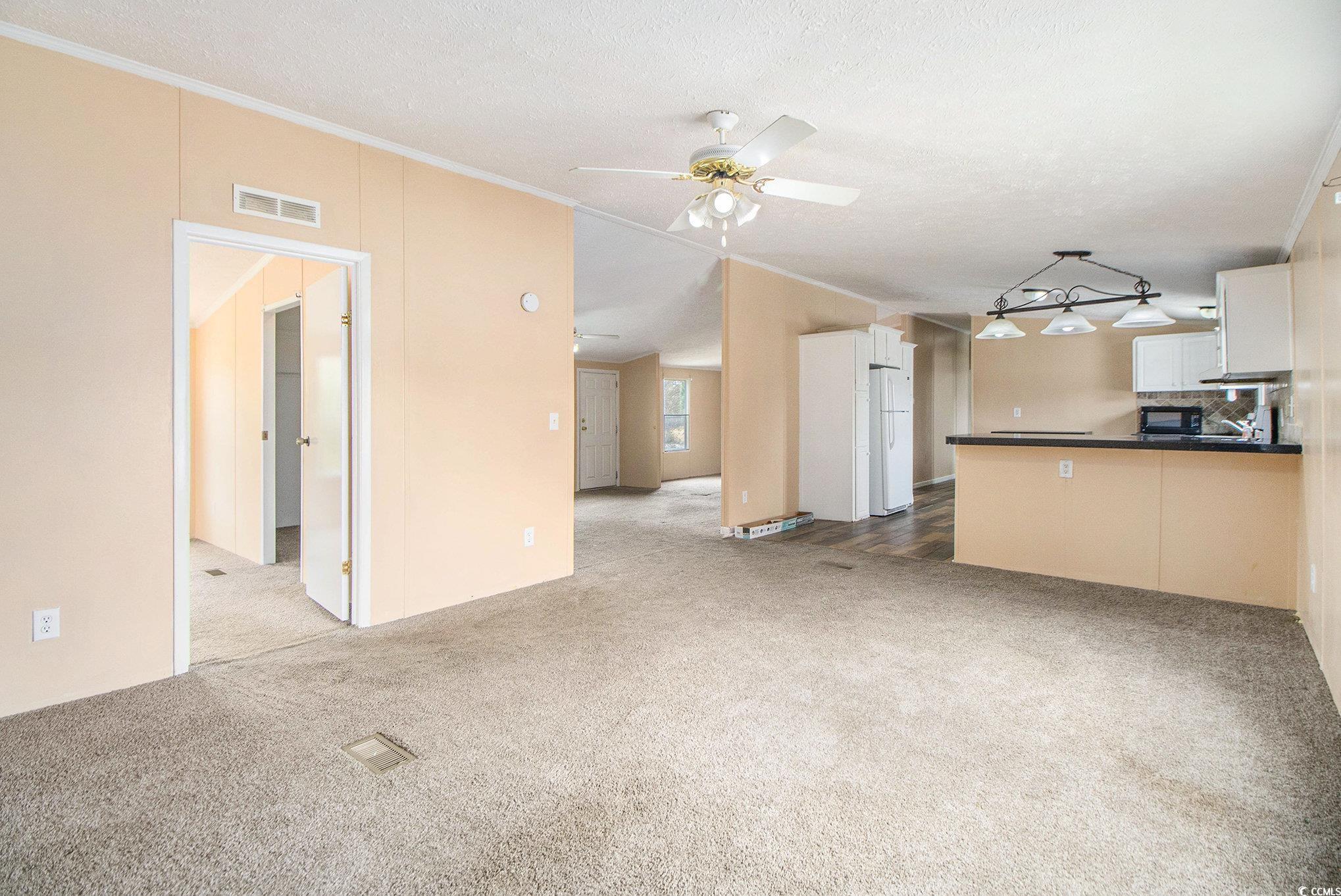 3804 Stern Drive Conway, SC 29526 - Photo 10 of 38 Unfurnished living room with light colored carpet, crown molding, a textured ceiling, and a ceiling fan