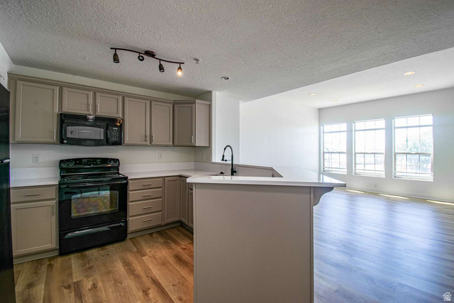 4276 South Main Street, Unit 303 Murray, UT 84107 - Photo 4 of 20 Open-concept kitchen featuring light-toned cabinetry, a built-in microwave, and a black range