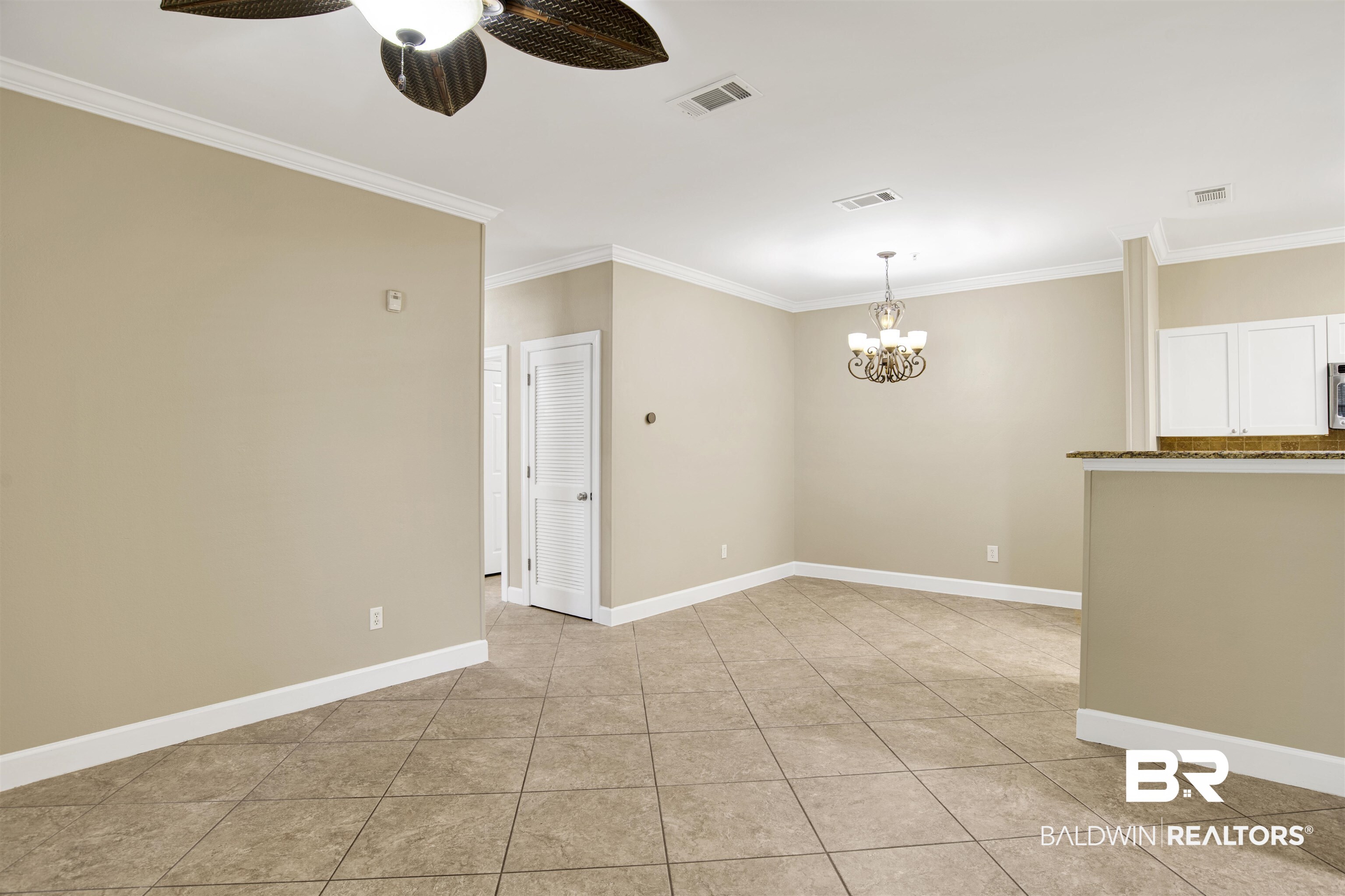 450 Park Avenue, Unit 202 Foley, AL 36535 - Photo 5 of 18 Spare room featuring crown molding, light tile patterned flooring, a chandelier, and a ceiling fan