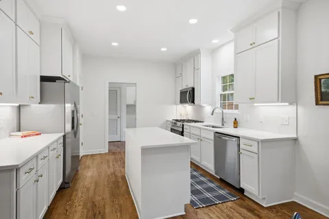 a kitchen with a sink a counter top space stainless steel appliances and cabinets