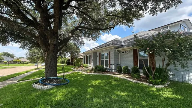 a front view of a house with garden and trees