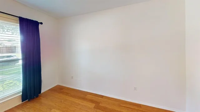 a view of a room with wooden floor and a window