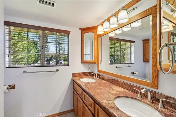 a bathroom with a granite countertop sink mirror and a large window