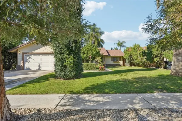 a front view of a house with a garden and trees