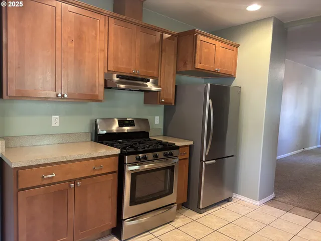 a kitchen with stainless steel appliances granite countertop a stove a refrigerator and a cabinets