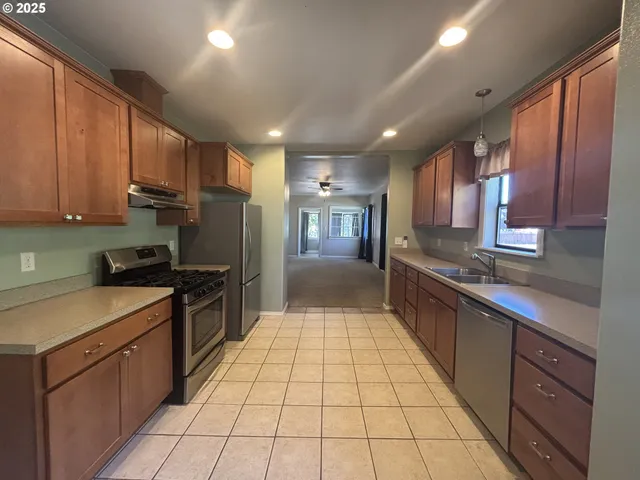 a large kitchen with stainless steel appliances granite countertop a stove a sink dishwasher and a refrigerator