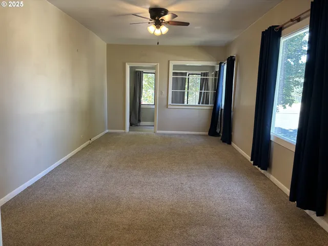 a view of a big room with windows and chandelier fan