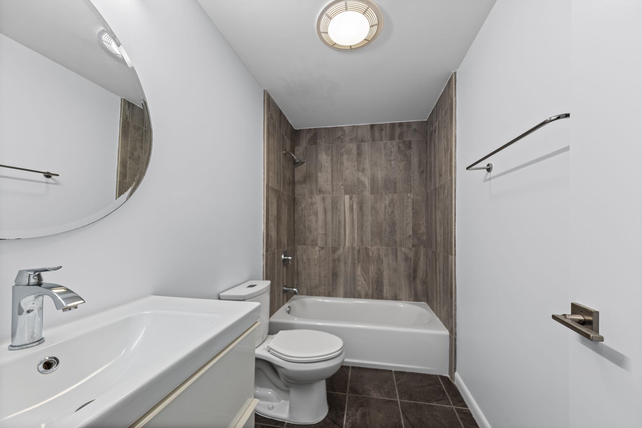 448 Tennessee Street Memphis, TN 38103 - Photo 12 of 39 Bathroom featuring a white vanity with integrated sink, chrome faucet, and a round wall mirror