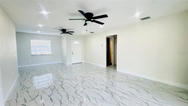 an empty room with a ceiling fan and window
