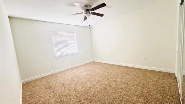 an empty room with a window and a fan