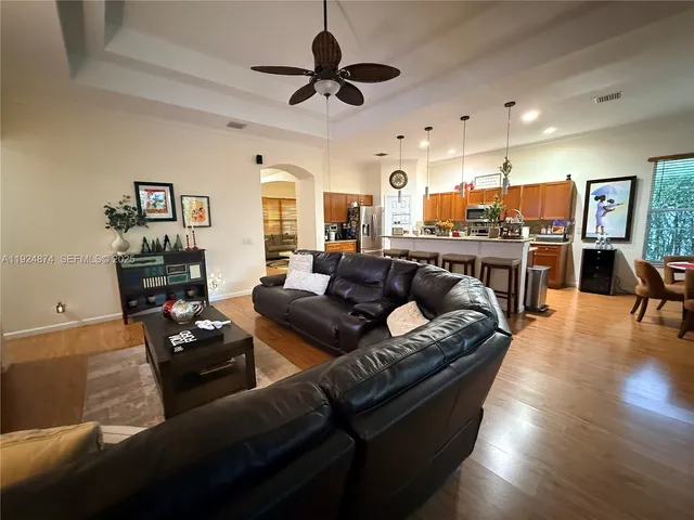 a living room with furniture kitchen view and a wooden floor