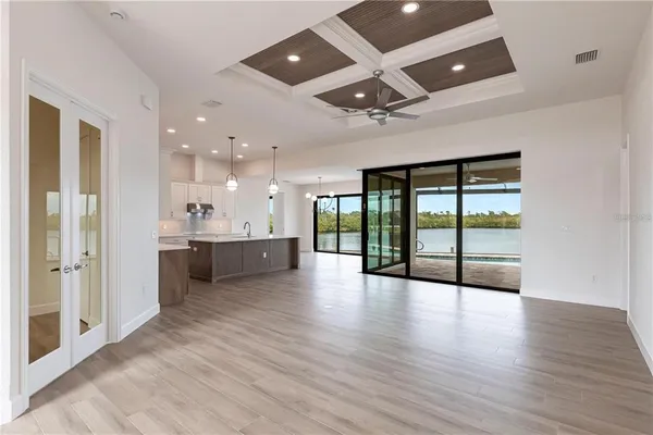 a view of an empty room with wooden floor and a ceiling fan