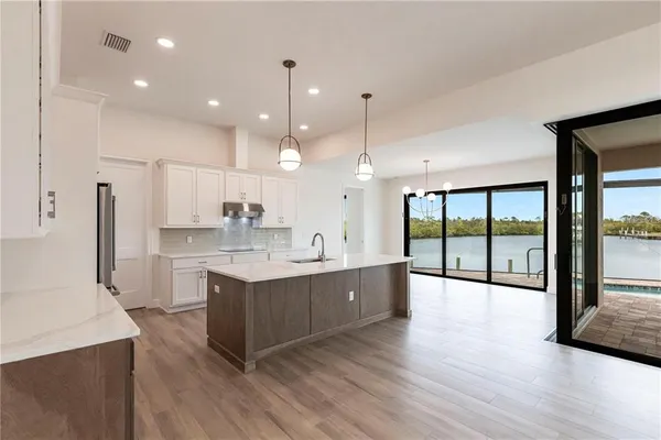 a large kitchen with stainless steel appliances kitchen island granite countertop a large counter top and wooden floors