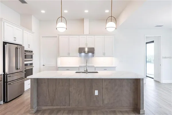a large kitchen with stainless steel appliances kitchen island a large counter top and a wooden floors