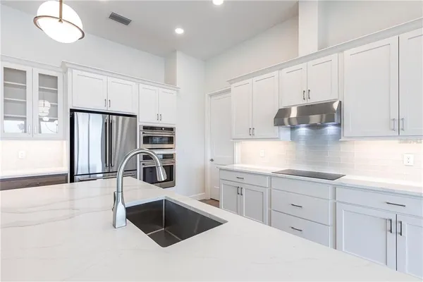 a large kitchen with granite countertop a large counter top appliances and cabinets