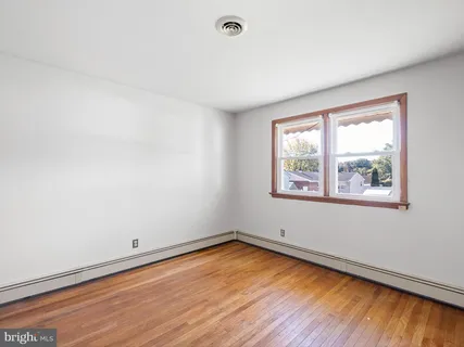 an empty room with wooden floor and window