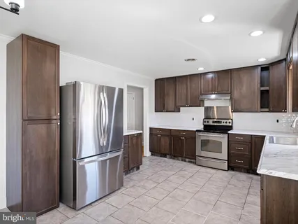 a kitchen with granite countertop stainless steel appliances a refrigerator a stove top oven and sink