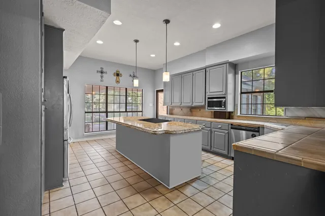 a large kitchen with granite countertop a large counter top and stainless steel appliances