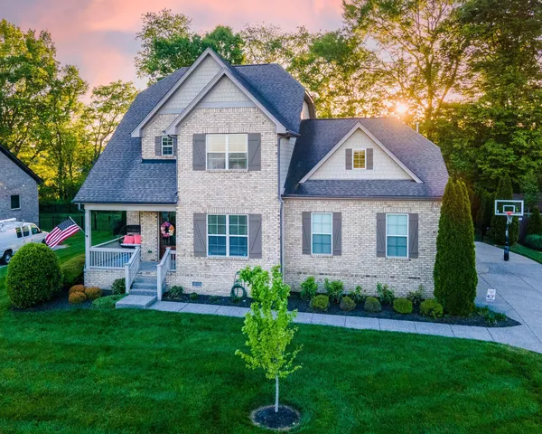 a front view of a house with a yard and green space