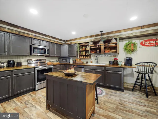 a kitchen with stainless steel appliances granite countertop a stove top oven a sink dishwasher a dining table and chairs with wooden floor