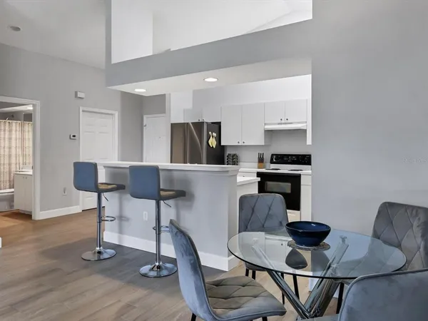 a kitchen with stainless steel appliances kitchen island granite countertop a dining table chairs and a refrigerator