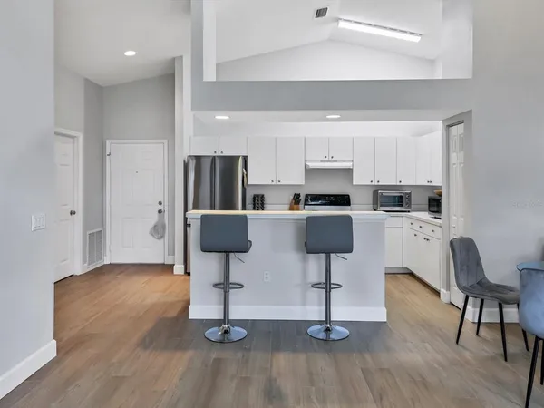 a living room with stainless steel appliances kitchen island granite countertop furniture and wooden floor