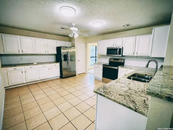 a kitchen with a sink a stove top oven a refrigerator and cabinets