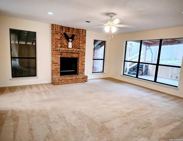an empty room with windows and fireplace